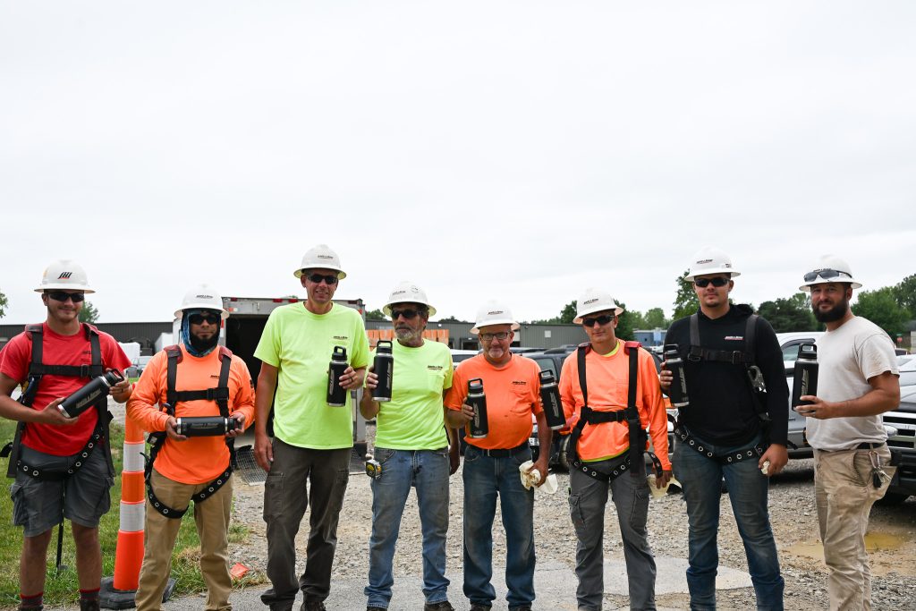 group of Janotta & Herner workers posed for a worksite photo, with their Yeti brand water bottles